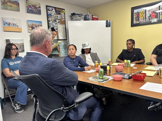 Rep. Peters speaks with young people at a table about cross-border sewage