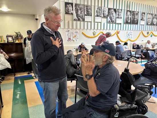 Rep. Peters speaks with a man in a wheelchair at Serving Seniors